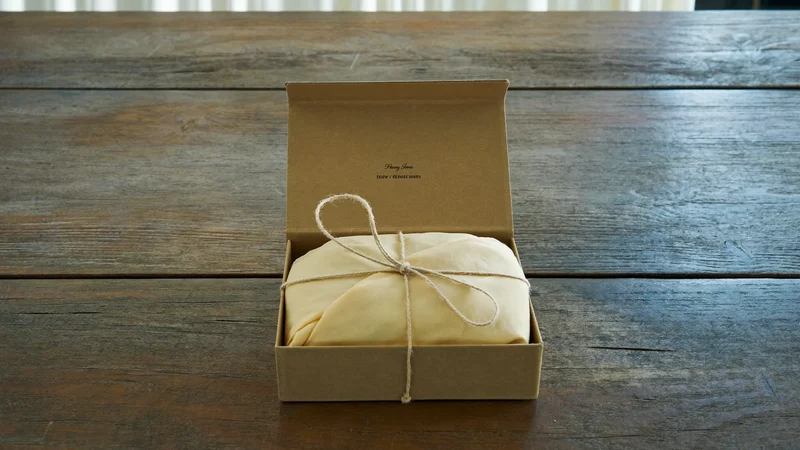 Geöffnete Geschenkbox aus Kraftpapier mit eingewickeltem Besteckset und Naturkordel